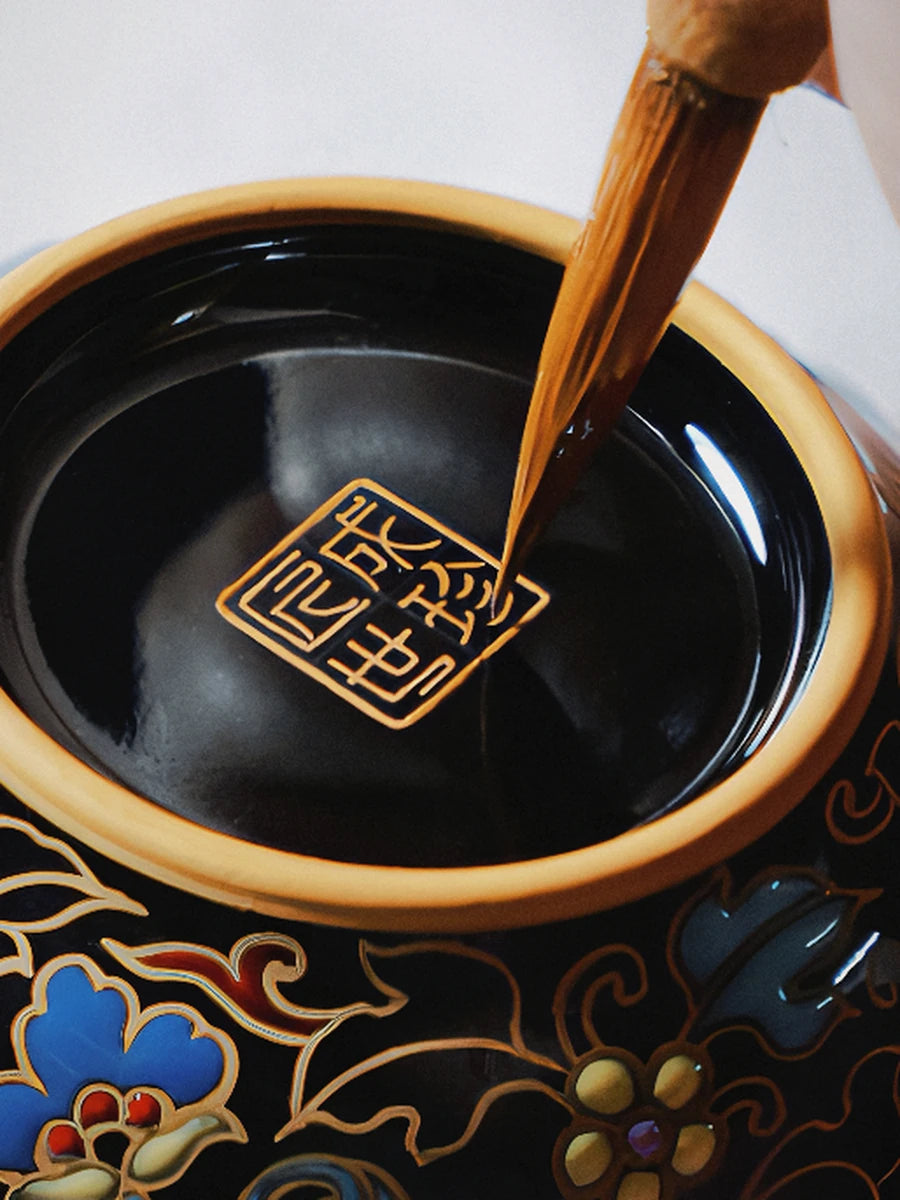 Brush painting a gold mark inside a dark porcelain bowl