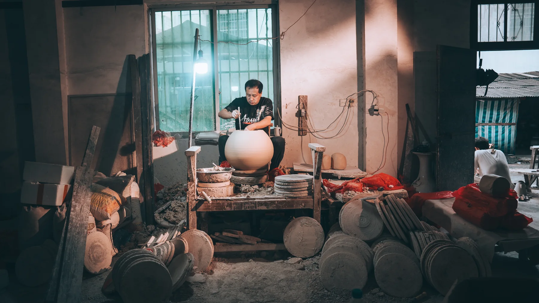 A porcelain artisan shaping a large vessel in a Jingdezhen workshop