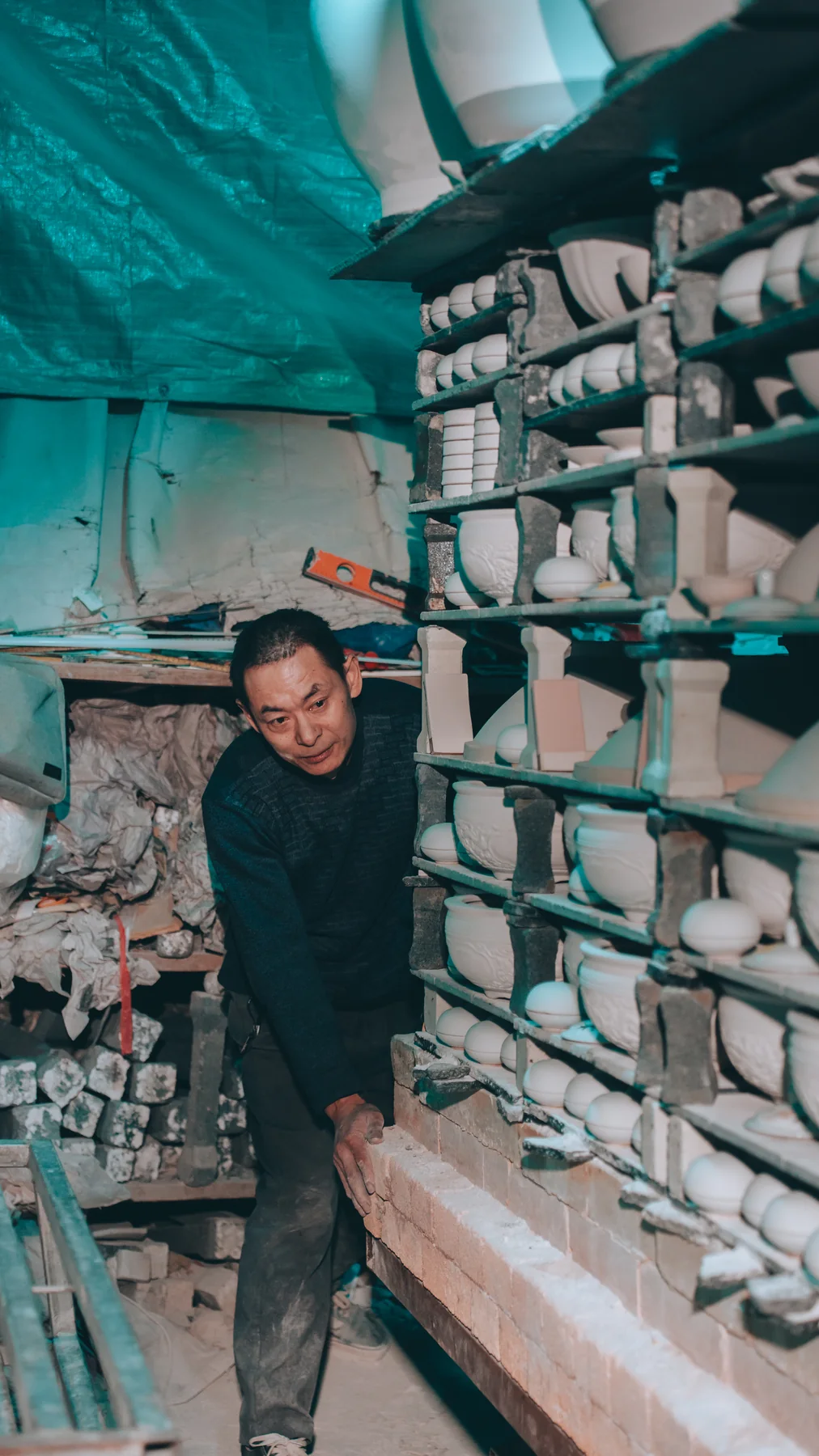 A kiln worker arranging porcelain vessels for firing